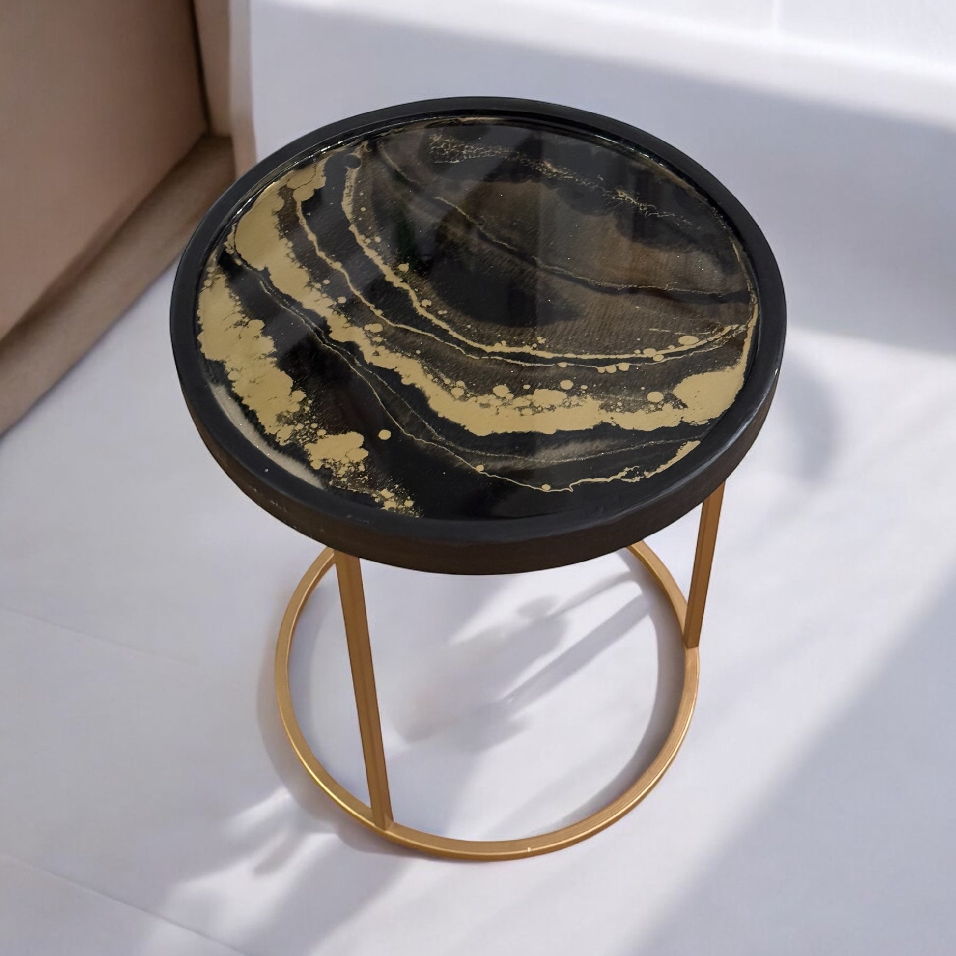 Moderner Couchtisch Beistelltisch aus Resin mit einzigartigem Design in Schwarz und Gold, perfekt als stilvolle Wohnzimmereinrichtung.