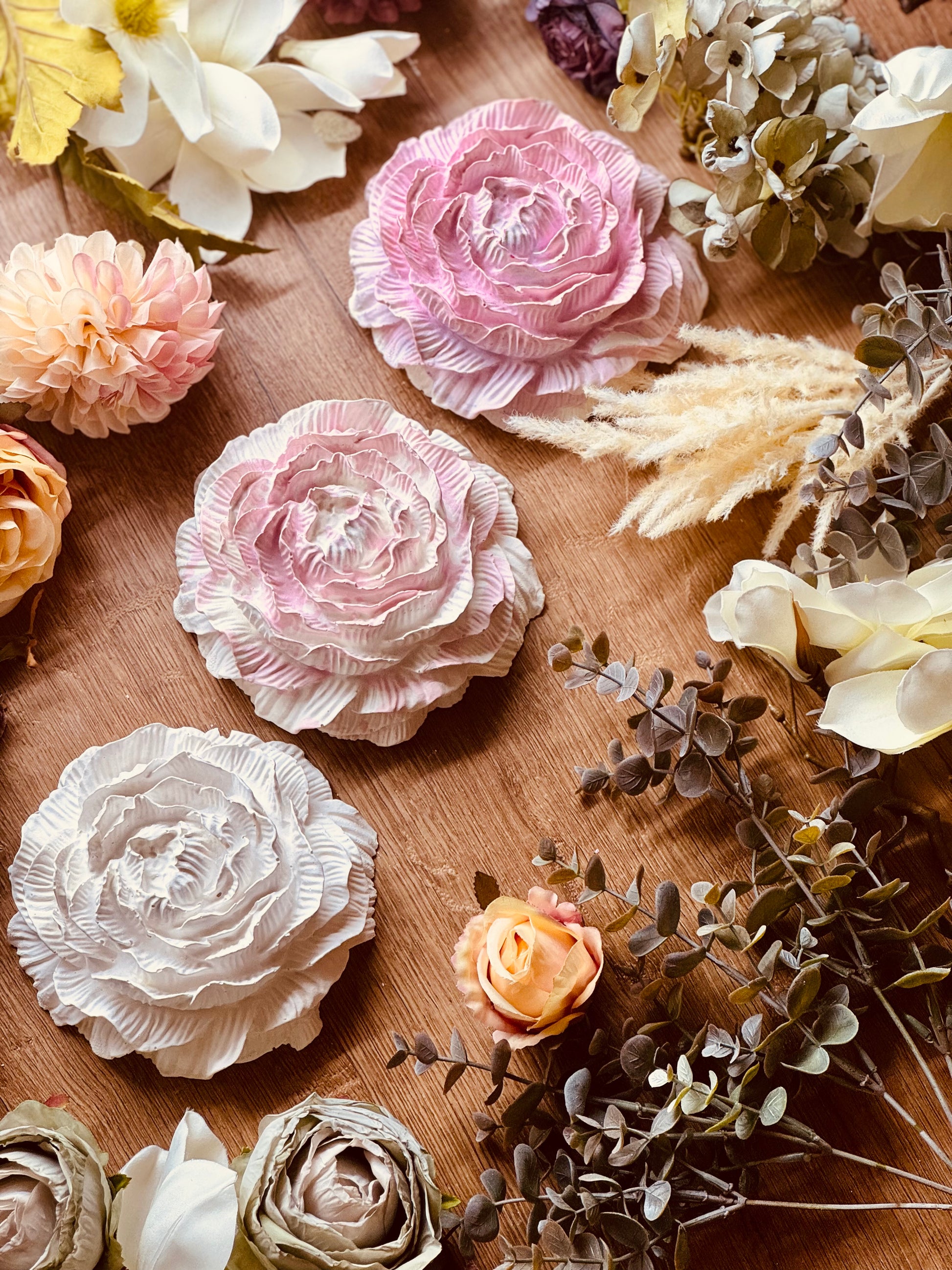 Zart gestaltete Rosenblüten aus Keramik in Rosa, Pink und Creme, dekorativ mit getrockneten Blumen arrangiert, ideale Geschenkidee für Liebhaber floraler Dekoration