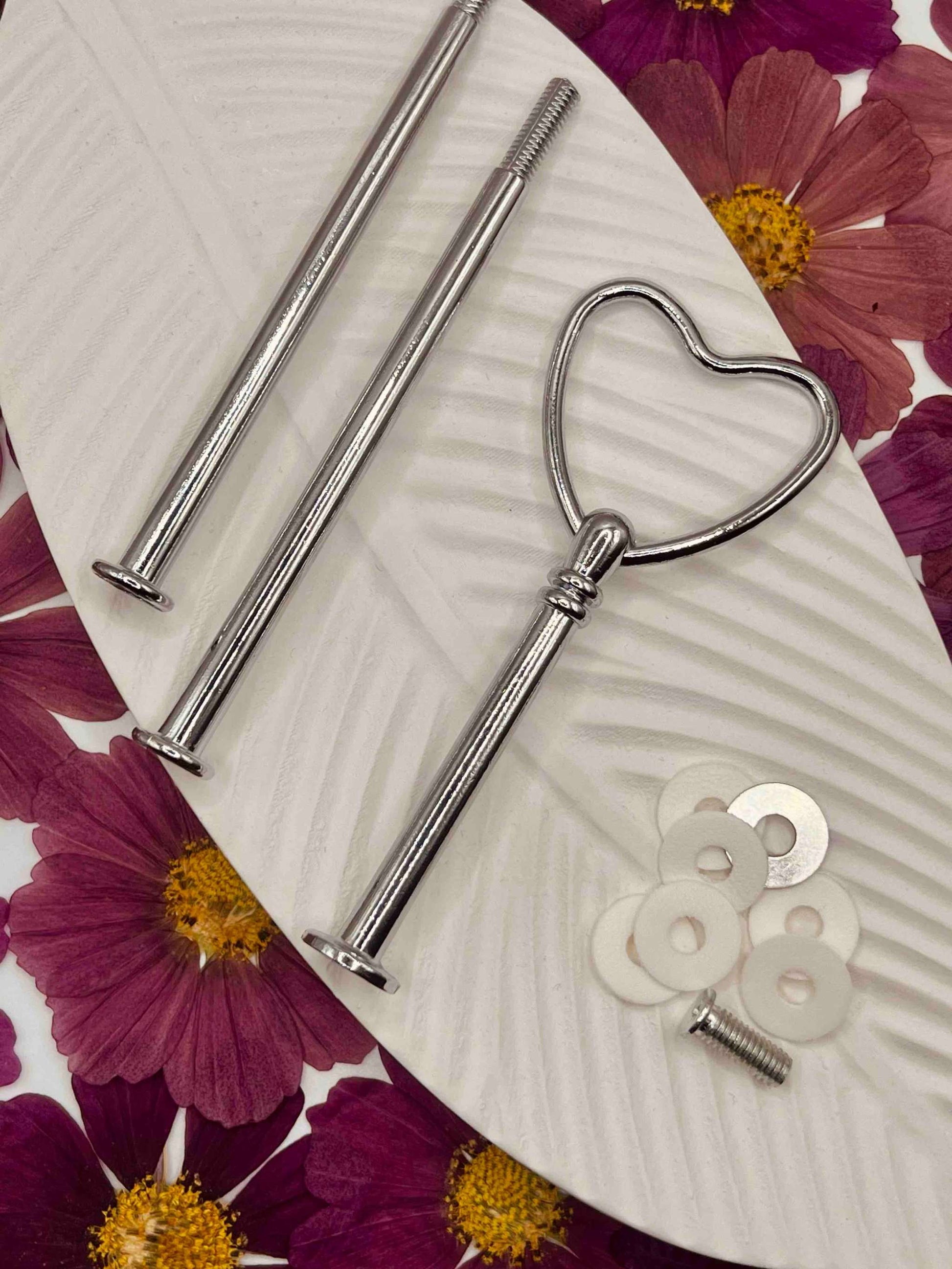 Heart-shaped silver etagerenstange with mounting accessories on floral background.